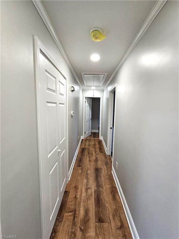 hall featuring dark wood-style floors, attic access, crown molding, and baseboards