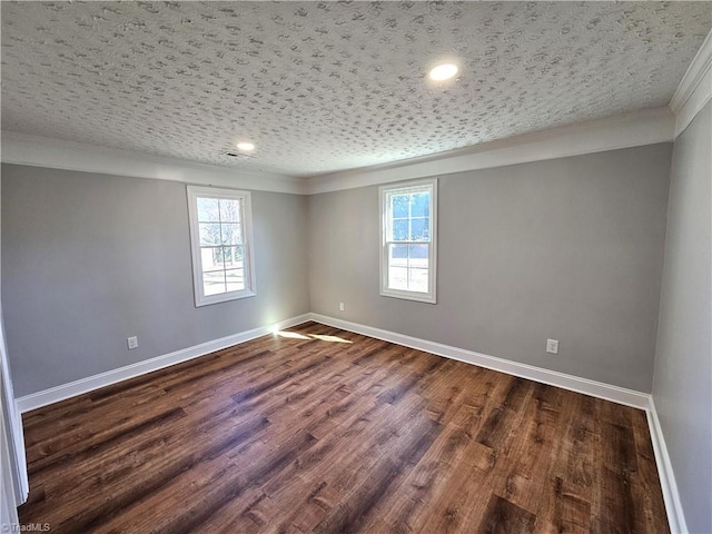 spare room with dark wood-type flooring, crown molding, baseboards, and a textured ceiling