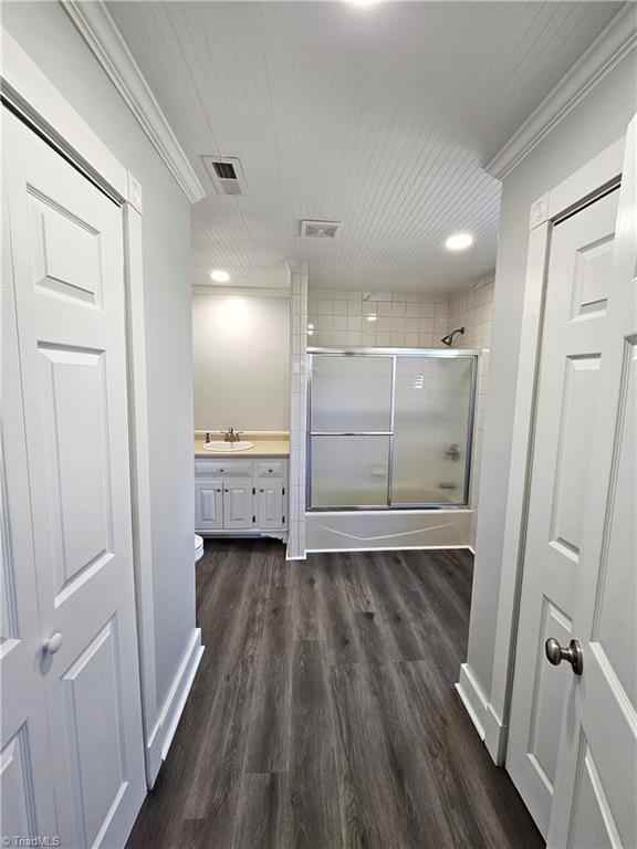 bathroom with visible vents, vanity, wood finished floors, and crown molding