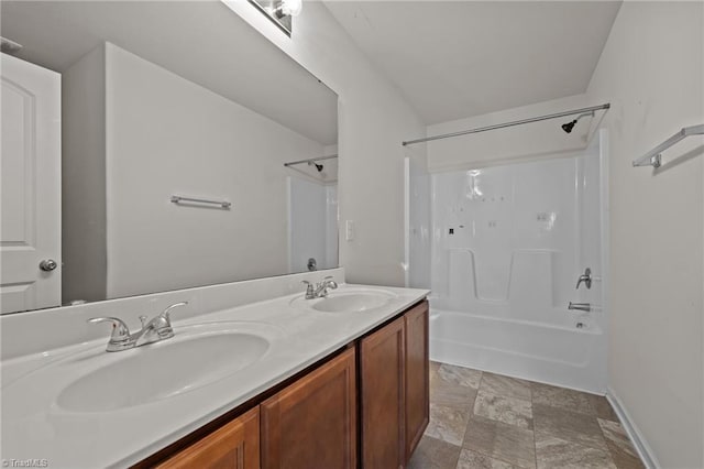 bathroom featuring double vanity, a sink, shower / tub combination, and baseboards