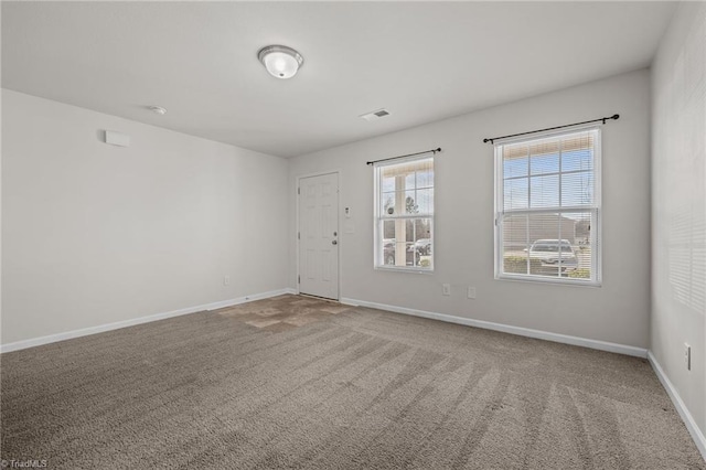 carpeted spare room with visible vents and baseboards