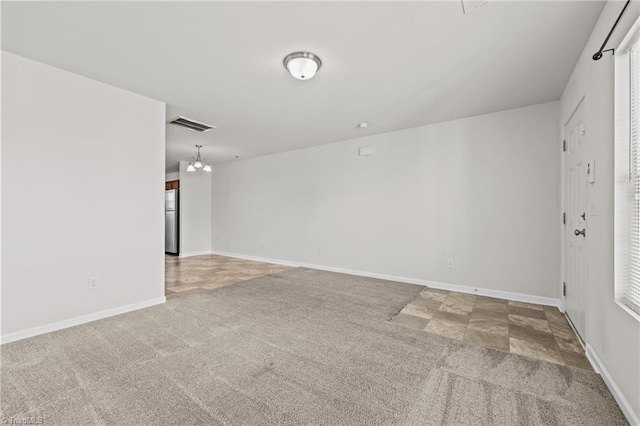 unfurnished room with carpet, visible vents, and baseboards