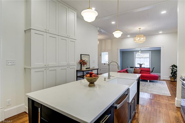 kitchen with hardwood / wood-style floors, light countertops, open floor plan, and a sink