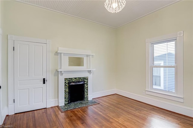 unfurnished living room with hardwood / wood-style flooring, baseboards, and a tile fireplace