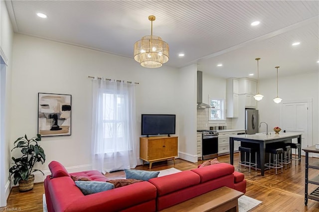 living room featuring recessed lighting, baseboards, an inviting chandelier, and wood finished floors