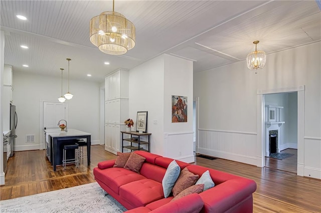 living area featuring wood finished floors, visible vents, baseboards, an inviting chandelier, and recessed lighting