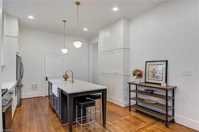 kitchen featuring visible vents, light countertops, white cabinets, stainless steel appliances, and wood-type flooring