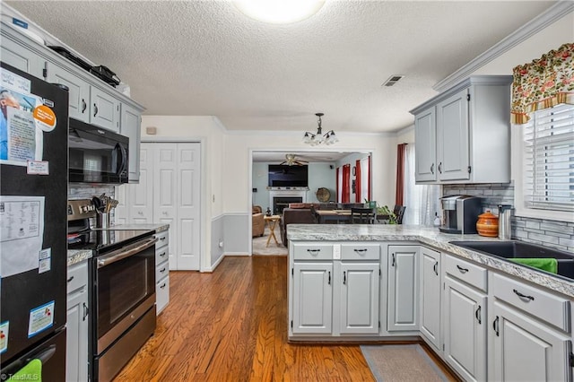 kitchen featuring gray cabinets, tasteful backsplash, black appliances, hardwood / wood-style flooring, and kitchen peninsula