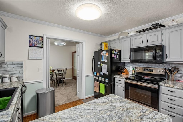 kitchen featuring crown molding, tasteful backsplash, a textured ceiling, light stone countertops, and black appliances