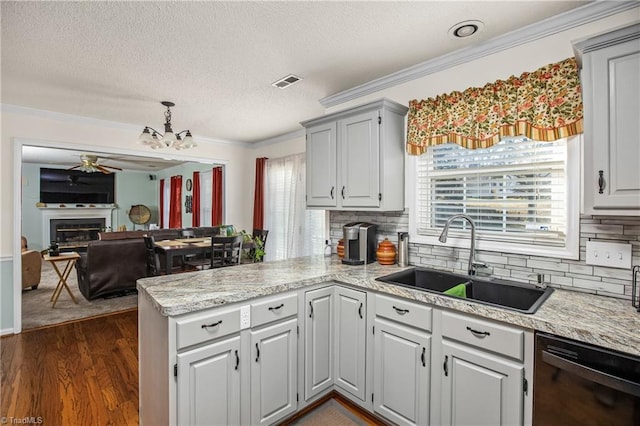 kitchen with crown molding, black dishwasher, sink, and kitchen peninsula