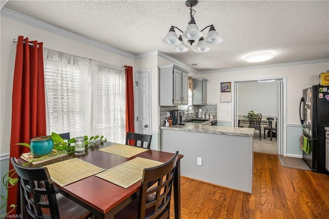 dining area with wood-type flooring, sink, and crown molding