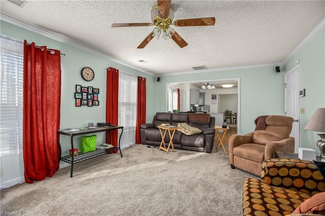 living room featuring ceiling fan, ornamental molding, a textured ceiling, and carpet