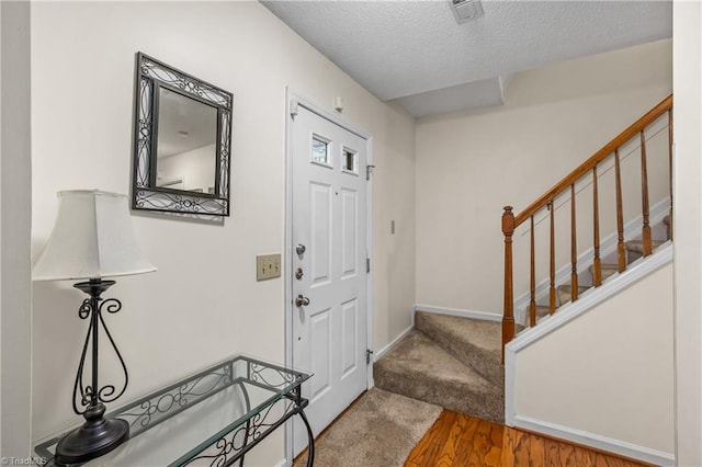 entryway with carpet floors and a textured ceiling