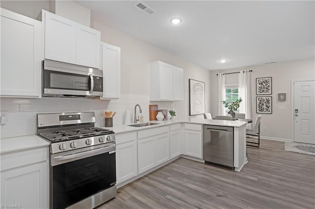 1868 Autumn Mist Dr, Winston-Salem, NC 27103 - kitchen featuring appliances with stainless steel finishes, backsplash, a peninsula, white cabinets, and light countertops