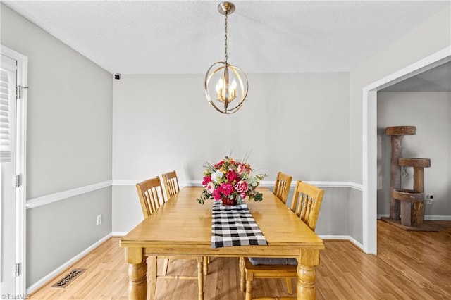 dining space featuring light hardwood / wood-style flooring and a notable chandelier