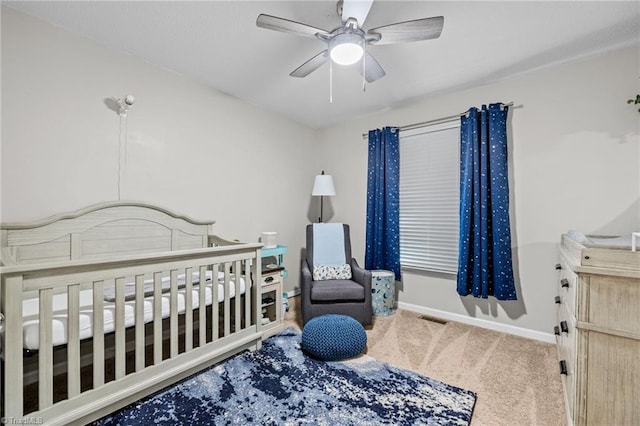 bedroom featuring carpet, a nursery area, and ceiling fan