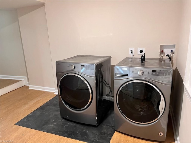 clothes washing area featuring light wood-type flooring and washer and clothes dryer