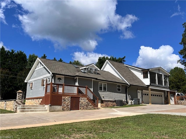 view of front of home featuring a front lawn, central AC unit, and a garage