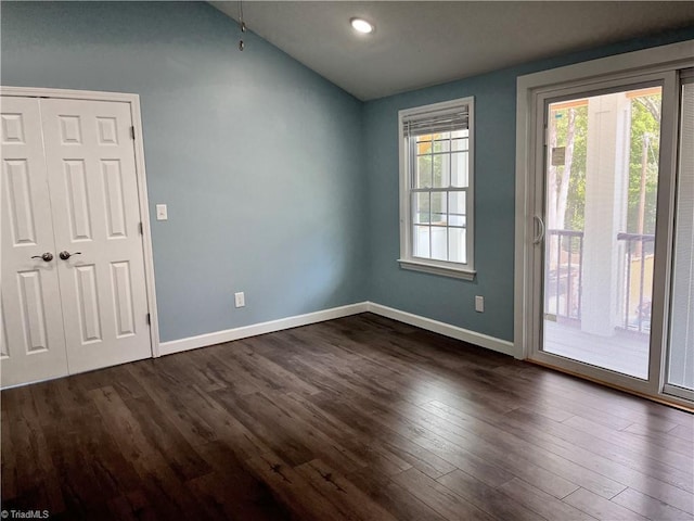 unfurnished room with lofted ceiling and dark hardwood / wood-style flooring