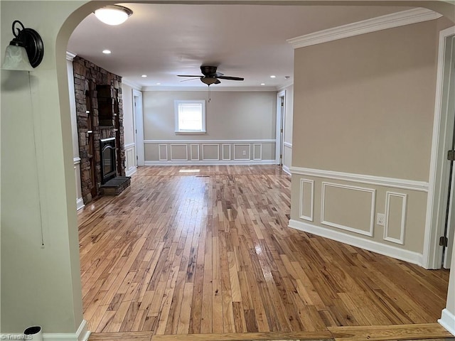 unfurnished living room with light wood-type flooring, a fireplace, ornamental molding, and ceiling fan