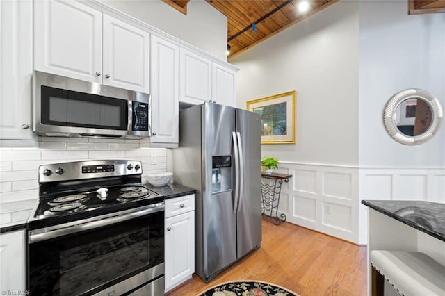 kitchen with backsplash, white cabinetry, stainless steel appliances, light wood finished floors, and wood ceiling