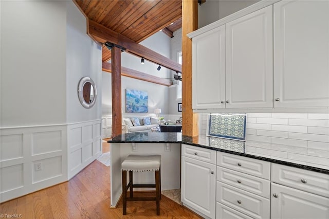 kitchen featuring backsplash, white cabinetry, and wood ceiling