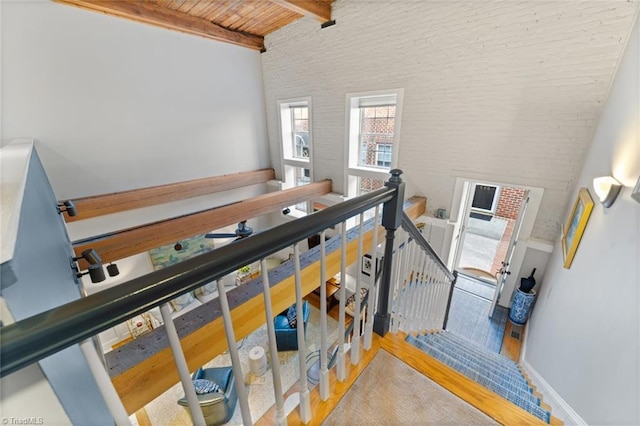 stairway with beamed ceiling, baseboards, a high ceiling, and wood ceiling