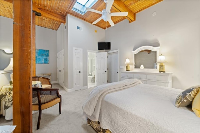 carpeted bedroom featuring baseboards, beamed ceiling, wood ceiling, a skylight, and ensuite bathroom