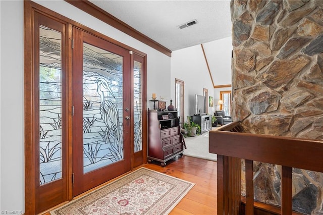 foyer with vaulted ceiling, wood finished floors, and visible vents