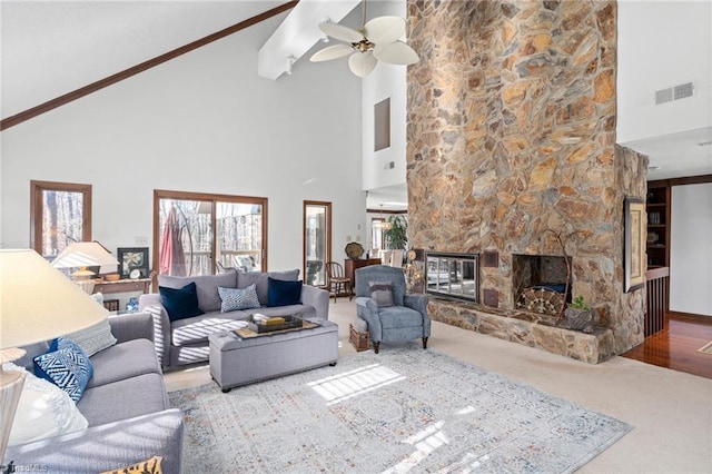 carpeted living room featuring a stone fireplace, vaulted ceiling, plenty of natural light, and visible vents