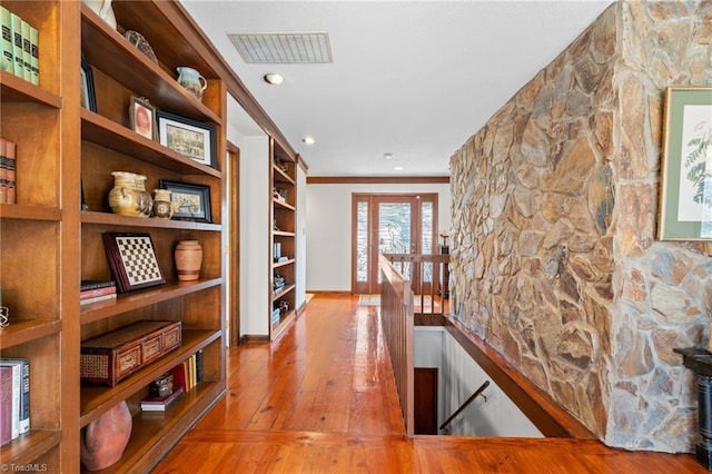 hall featuring an upstairs landing, visible vents, baseboards, and hardwood / wood-style floors