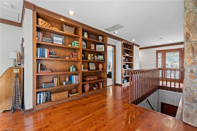 sitting room featuring built in shelves, crown molding, an upstairs landing, recessed lighting, and wood finished floors