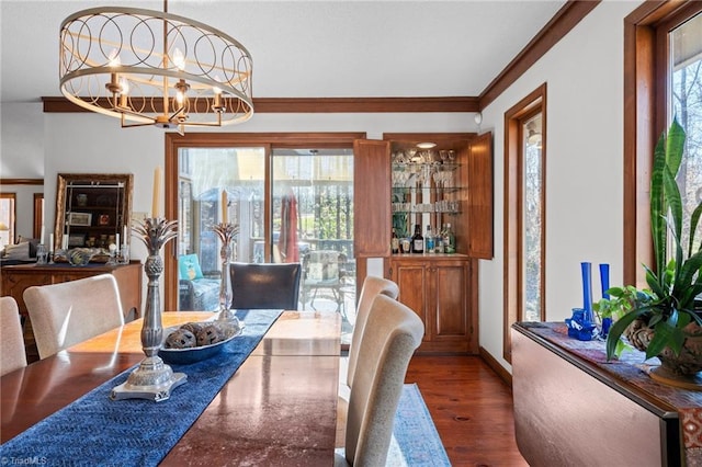 dining room with crown molding, a notable chandelier, wood finished floors, and plenty of natural light