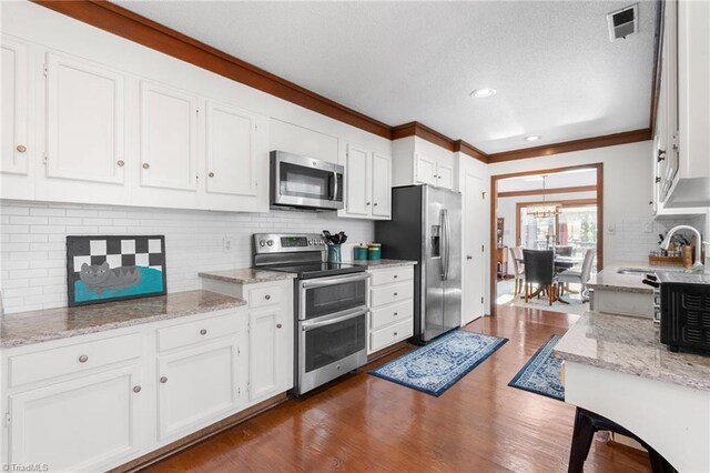 kitchen with dark wood-style floors, white cabinets, stainless steel appliances, and a sink