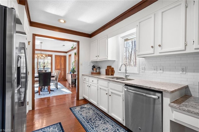 kitchen featuring a sink, stainless steel appliances, a wealth of natural light, and ornamental molding