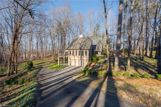 exterior space with a garage, driveway, and a chimney