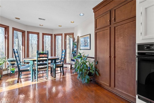 dining area featuring recessed lighting, plenty of natural light, wood finished floors, and visible vents