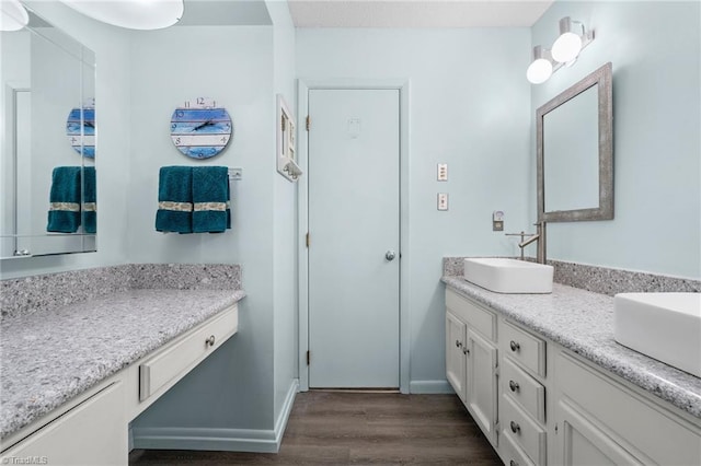 full bath featuring double vanity, wood finished floors, baseboards, and a sink