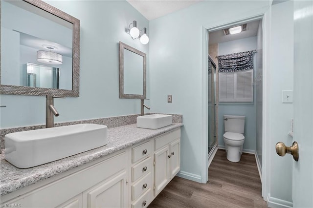 full bathroom with a sink, visible vents, toilet, and wood finished floors