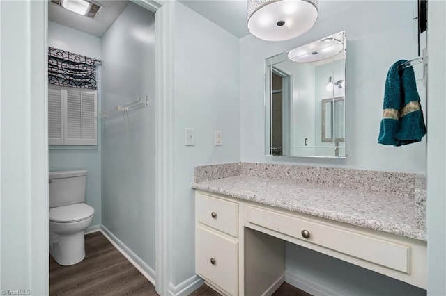 bathroom with visible vents, toilet, wood finished floors, baseboards, and vanity