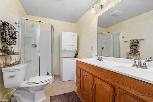 full bath featuring a sink, stacked washer and dryer, a shower stall, and wallpapered walls