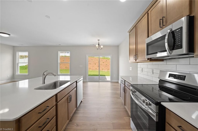 5751 Siler St, Trinity, NC 27370 - kitchen with backsplash, appliances with stainless steel finishes, a sink, light countertops, and light wood-style flooring