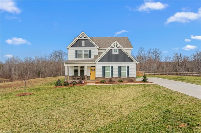 craftsman-style house with board and batten siding, fence, a porch, a front yard, and driveway