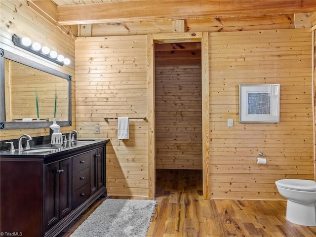 bathroom with vanity, wood walls, and wood-type flooring