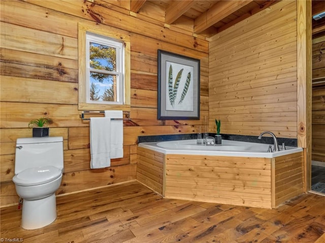 bathroom with a bathing tub, beamed ceiling, wood-type flooring, and toilet