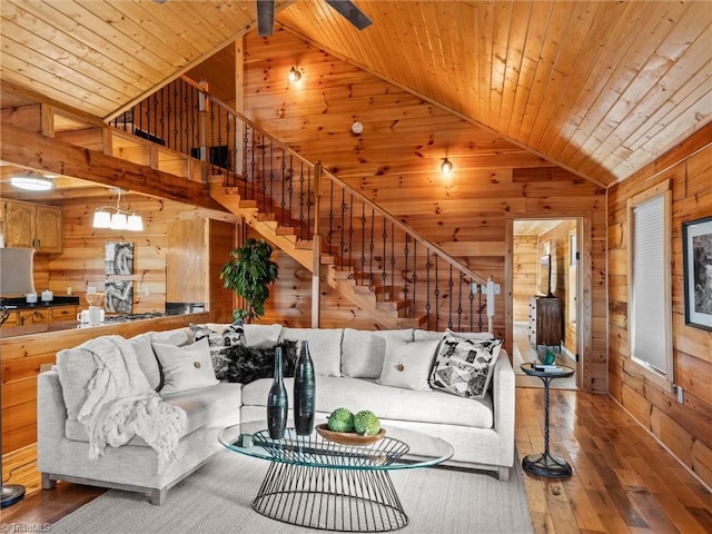 living room with wood walls, wood-type flooring, high vaulted ceiling, and wooden ceiling