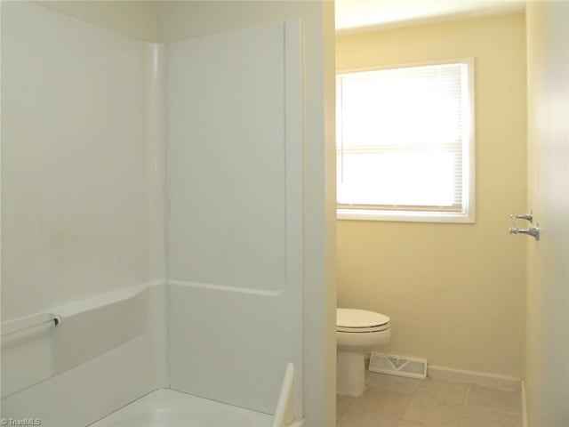 bathroom featuring a bathing tub, tile patterned flooring, and toilet