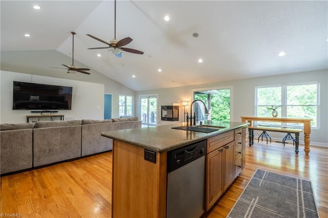 kitchen with a sink, light wood-type flooring, an island with sink, vaulted ceiling, and stainless steel dishwasher