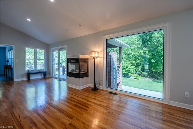 unfurnished living room featuring lofted ceiling, a wealth of natural light, baseboards, and visible vents