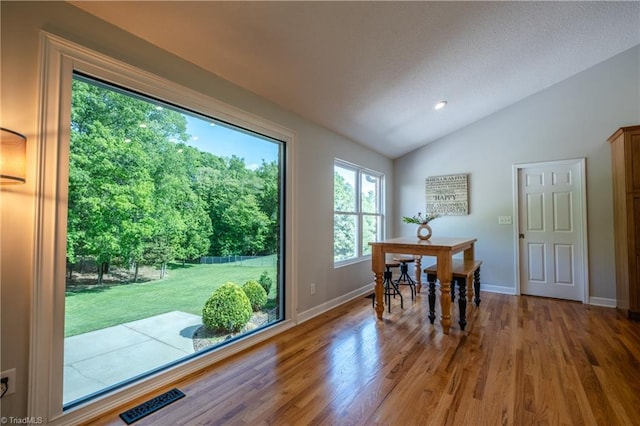 dining area with baseboards, visible vents, wood finished floors, and lofted ceiling